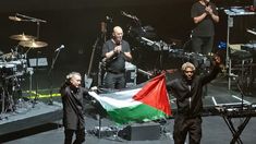 Robert Del Naja y Grant Marshall exhiben la bandera de Palestina.