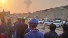 Trabajadores petroleros frente al hongo de humo que provocó el ataque a la refinería. Trabajadores petroleros frente al hongo de humo que provocó el ataque a la refinería.