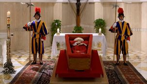 Está expuesto en un simple ataúd de madera abierta y en sus manos lleva el rosario.