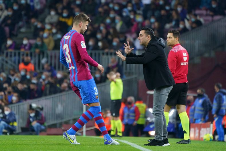 Xavi Hernández da indicaciones a Gerard Piqué.