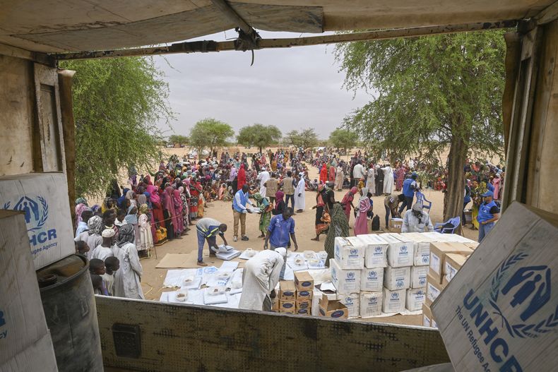 Trabajadores de Acnur descargan kits con asistencia de emergencia para distribuirlos a los refugiados sudaneses recién llegados al campamento de Madjigilta