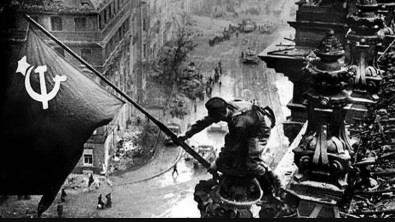 Un soldado del ejército rojo agita la bandera con la hoz y el martillo en la cúpula del Reichstag.