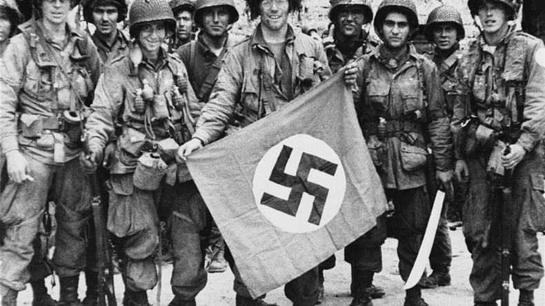 Soldados americanos sostienen una bandera nazi capturada en el frente occidental.