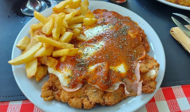 La milanesa napolitana con papas fritas es uno de los platos típicos de bodegón porteño. La milanesa napolitana con papas fritas es uno de los platos típicos de bodegón porteño.
